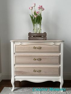 a white dresser with flowers on top of it