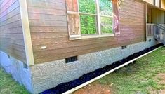 the side of a house that has been gutted with blue mulch and grass