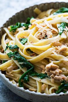 pasta with tuna and arugula sauce in a bowl on a marble table top