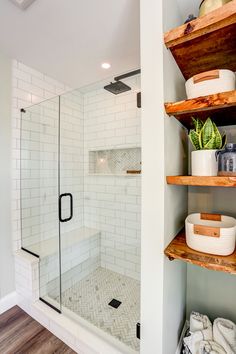 a walk in shower sitting next to a wooden shelf