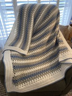 a crocheted blanket sitting on top of a chair in front of a window