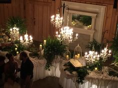 a room filled with lots of tables covered in white tablecloths and chandeliers