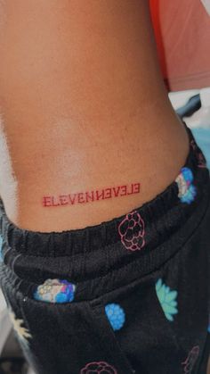 a woman's lower back tattoo with the word eleveneven on her left side