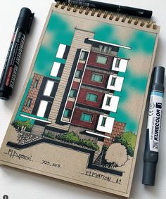 a notebook with a drawing of a building on it next to two markers