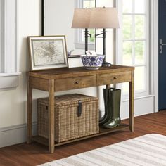 a wooden table with two baskets underneath it and a lamp next to it on a rug