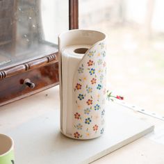 a vase sitting on top of a table next to a cup and other items in front of a window