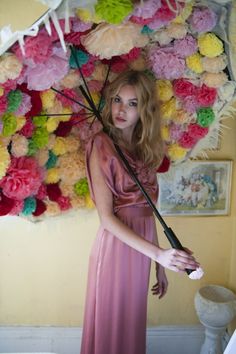 a woman in a pink dress holding an umbrella over her head with flowers on it