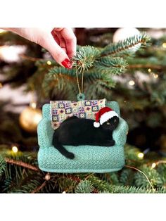 a black cat ornament hanging from a christmas tree with a santa hat on it