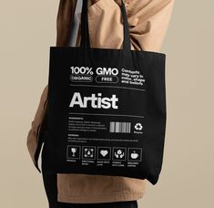 a person holding a black shopping bag with the words artist printed on it