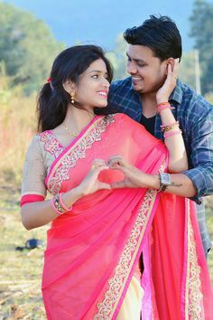 a man and woman standing next to each other in front of a field with trees