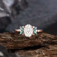 an oval diamond ring with turquoise stones in the center on top of a piece of wood