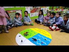 a group of children sitting on the floor in front of a rug with animals painted on it