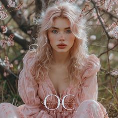 a woman sitting on the ground next to a tree with pink flowers in her hair