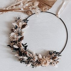 a wreath made out of dried flowers and leaves on top of a white table cloth