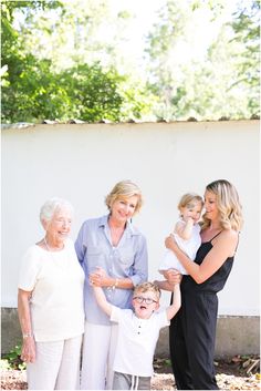 an older woman and two young boys with their mother in front of a white wall