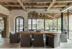 the dining room table is surrounded by gray chairs and an oval chandelier that hangs from the ceiling