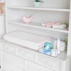 a baby crib in the corner of a room with white furniture and accessories on it