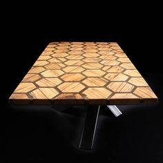 a square wooden table with metal legs on a black background in the middle of the room