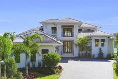 a large white house with palm trees in the front yard