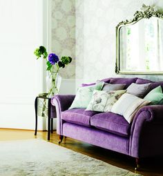 a pink couch sitting in front of a wall with a mirror on it's side