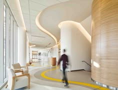 a man is walking through an office lobby with yellow lines on the floor and walls