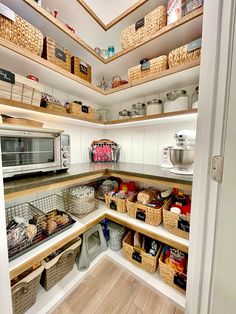 an organized pantry with baskets, food and other items on the shelves in front of the microwave