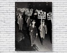 black and white photograph of men walking down the street holding signs that read we want beer