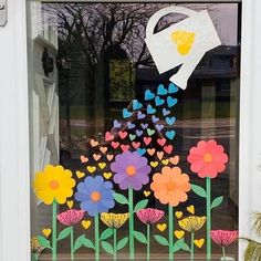 a window decorated with flowers, butterflies and a watering can in the center is a paper cutout