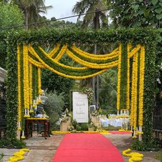 an outdoor ceremony with yellow flowers and greenery on the walls, red carpeted walkway