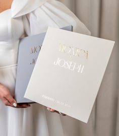 a woman in a white dress holding two books with gold foil lettering on the cover