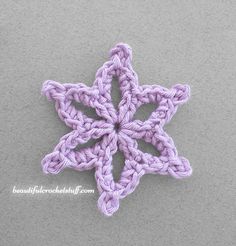 a crochet snowflake is shown on a gray surface