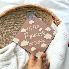 a person is holding up a sign that says little princess on board in front of a wicker basket