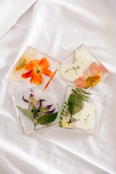 four different types of flowers in small glass containers on a white sheeted tablecloth