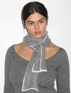 a woman wearing a gray sweater with a scarf around her neck