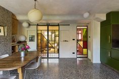 a dining room table with chairs and a vase on top of it next to a doorway