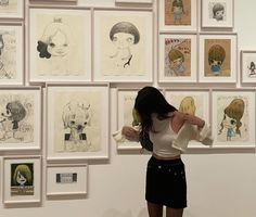 a woman standing in front of a wall with drawings on it