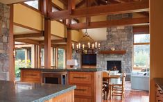 a large kitchen with an island in the middle and wood cabinets on both sides, along with a stone fireplace