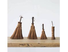 four wooden brooms are lined up on a table