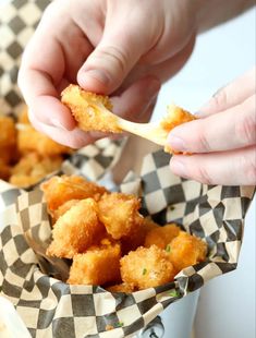 a person is dipping something into some kind of fried food in a paper basket with checkered wrapping