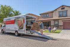 a man unloading boxes from the back of a moving truck in front of a house