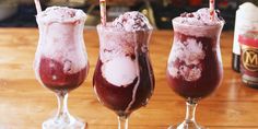 three glasses filled with ice cream sitting on top of a wooden table