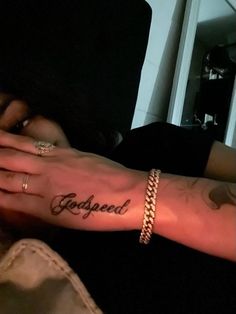 a person with a tattoo on their arm and the word godgaed written in cursive writing