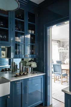 a kitchen with blue cabinets and marble counter tops, along with an open door leading to the dining room