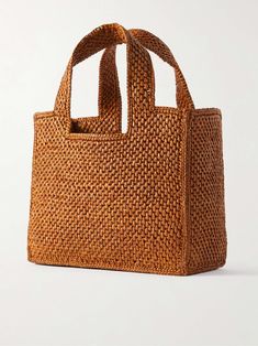 a brown woven bag sitting on top of a white surface