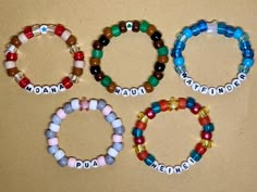 four bracelets with name charms on them sitting next to each other in front of a brown background