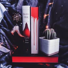 some books and a cacti are sitting on top of a book shelf in front of a black background