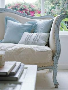 a white couch sitting next to a window in a living room with pillows on top of it