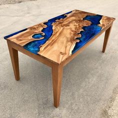 a table made out of wood with blue paint on the top and bottom, sitting in an empty parking lot