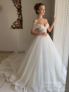 a woman in a white wedding dress standing next to a wall with beads on it