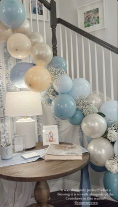 balloons are hanging from the bannister above a table with an open book on it